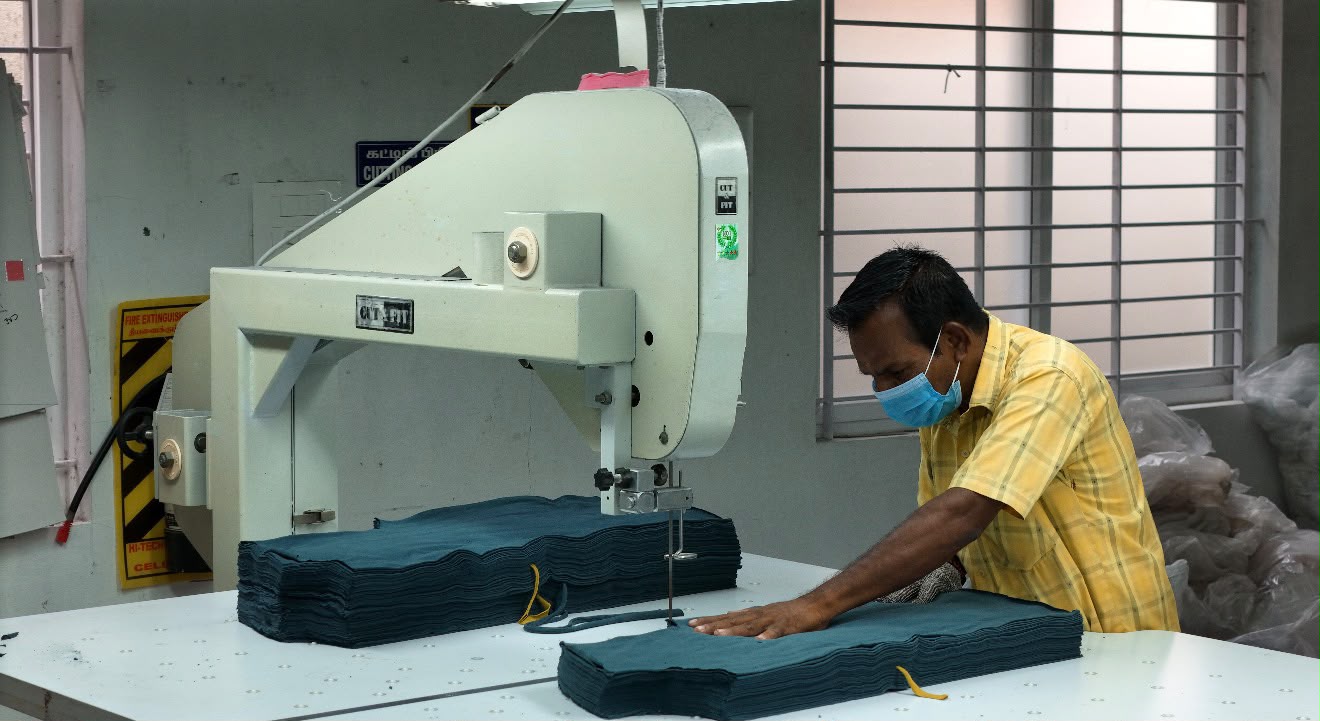 Cutting master sectioning graded fabric panels on a band-knife machine at Ayyappa Textiles